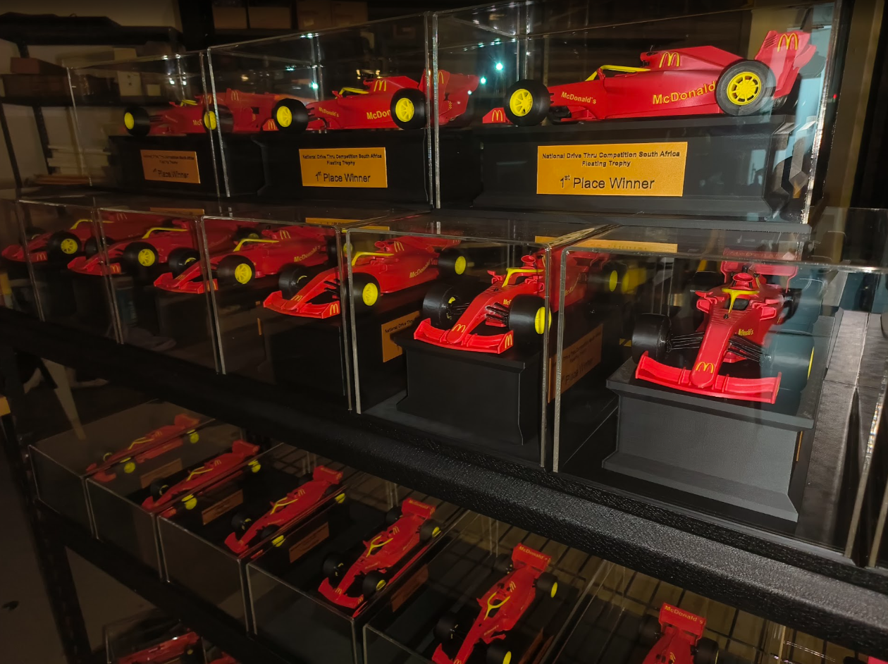 McDonald’s red race car trophies with yellow wheels in transparent display cases